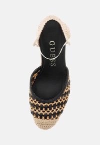Espadrillas tessute nere e beige con punta chiusa, dettagli decorativi in catena dorata e tomaia in tessuto testurizzato. Soletta nera con logo.
