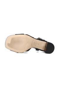 Zwarte sandalen met hoge hakken, voorzien van een glad bovenwerk, een gestructureerde zool en een gouden gesp. De zool is beige met een geribbeld patroon voor extra grip.