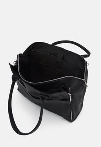 Sort lædertaske med lynlåslukning, rummeligt indre, flere lommer og to håndtag. Glat tekstur og enkelt design.