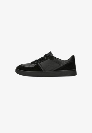 Zwarte lage sneaker met getextureerd leer en suède panelen, vetersluiting en platte rubberen zool, gezien vanaf de buitenzijde op een witte achtergrond.