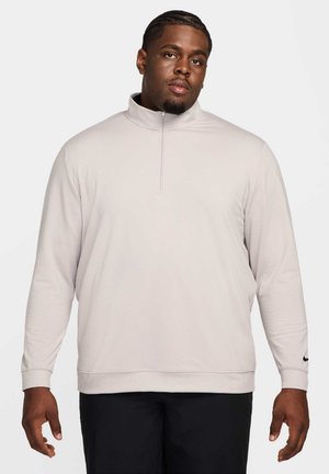 Light gray long-sleeve pullover with a half zip, ribbed cuffs, and a Nike logo accent on the left sleeve. Smooth texture throughout.