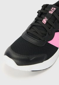 Baskets en mesh noir avec une accent rose, des superpositions synthétiques texturées, un bout arrondi et des lacets noirs plats sur une semelle blanche.