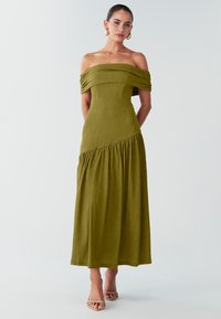 Olivengrøn maxikjole med bare skuldre, rynkede ærmer, struktureret stof og et udvidet nederdel. Ankel-lang med en afslappet pasform.