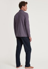 Langsleeve patroonhemd met een marineblauwe achtergrond en een geometrisch rood-wit ontwerp, gecombineerd met een paar effen marineblauwe broeken. Casual fit.