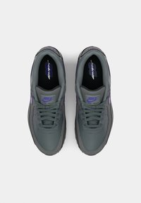 Gray Nike Air Max sneakers with purple accents, textured fabric upper, round laces, padded collar, and logo on tongue and insole.