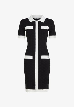 Svart tettsittende kjole med teksturert stoff, korte ermer, hvit krage og vertikale hvite striper; har to frontlommer med hvite detaljer.