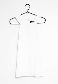 Witte mouwloze jurk aan een zwarte hanger, met een vierkante halslijn en geplooide schouderdetails. Glad stof met een eenvoudig ontwerp.