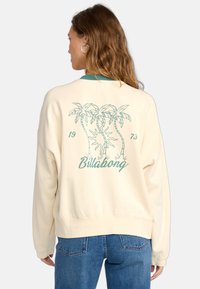 Cremefarbener Sweatshirt mit grünen Akzenten. Enthält Grafiken von Palmen und den Text "Billabong". Lässige Passform, gerippter Kragen und Bündchen.