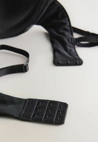 Reggiseno nero con tessuto liscio, spalline regolabili e chiusura a gancio con sei ganci sul retro. Coppa a forma arrotondata.