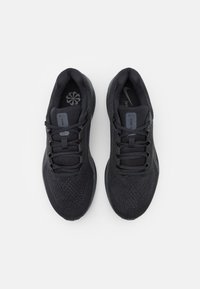 Chaussures de course Nike en mesh noir avec des surfaces texturées, des lacets plats et un col rembourré. Présente un logo sur la languette.