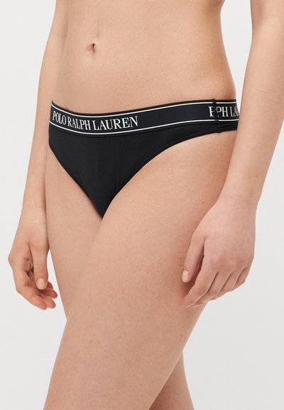 Juodos bikini kelnaitės su ryškiu pilku ir baltu logotipu ant juosmens. Slydus audinys, minimalus aprėptis ir klasikės kirpimas.