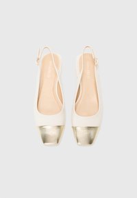 Vita slingback-skor med fyrkantig tå, med en metallisk guldcap på tåområdet och en slät yta. Tunnhäftande justerbar rem ingår.