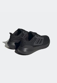 Zapatillas deportivas negras con un upper texturizado, suela de goma gruesa y tres franjas diagonales en el costado. Diseño ligero.