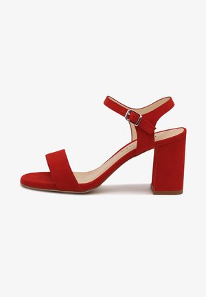 Czerwona zamszowa sandałka na wysokim obcasie typu blok z odkrytymi palcami, szerokim paskiem z przodu zapewniającym wsparcie oraz paskiem wokół kostki z klamrą.