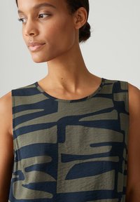 Sleeveless top featuring a dark navy and olive green abstract pattern. Soft, lightweight fabric with a round neckline and casual fit.