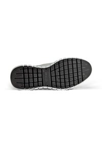Semelle de chaussure en caoutchouc noir avec des rainures profondes, un accent blanc le long du bord, et une empreinte de logo. La texture est structurée pour une meilleure adhérence.