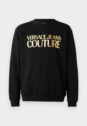 Svart hettegenser laget av en bomull-polyester blanding, med gulltrykket tekst "VERSACE JEANS COUTURE" på forsiden i fet skrift.