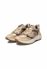 Zapatillas de piel beige con acentos metálicos, laterales texturizados y una suela gruesa blanca. Presenta ojales redondos y cordones para un ajuste seguro.