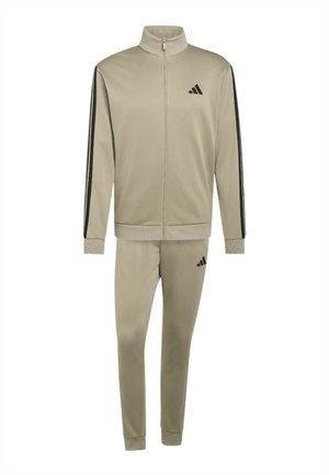 Chándal beige de Adidas con chaqueta de cremallera completa y pantalones a juego, con rayas negras en las mangas y logo de Adidas en el pecho y el muslo.