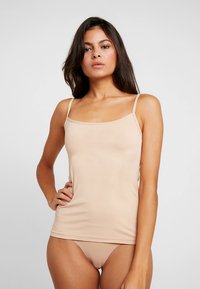 Nude camisole with thin straps, made of smooth, stretchy fabric. Simple, fitted design with a straight neckline and slight sheen.