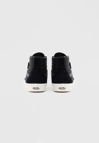 Czarne wysokie trampki z materiałów zamszowych i siatkowych, z wyściełanym kostką, białą gumową podeszwą i logo Vans na pięcie.