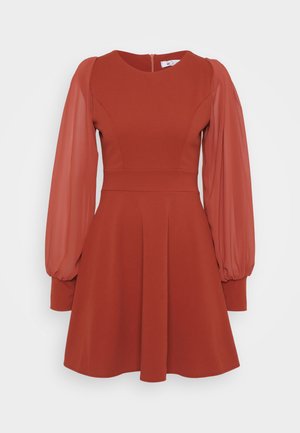 Abito rosso con maniche corte a sbuffo in tessuto trasparente, corpino aderente, gonna svasata e zip sul retro. Realizzato in tessuto testurizzato con una finitura liscia.