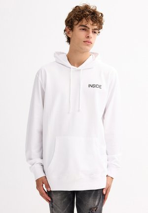 Sudadera blanca con capucha, con "INSIDE" impreso en negro en el pecho, presenta un bolsillo frontal y capucha con cordón, fabricada en suave tela de algodón.