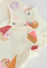 Body en crème douce pour bébé avec boutons-pression et illustrations imprimées d'un lapin rose, d'un chien marron et de formes géométriques en rose et orange.