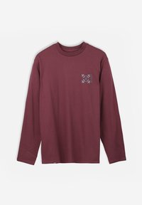T-shirt à manches longues bordeaux en tissu coton. Présente un petit design graphique bleu sur la poitrine gauche. Encolure arrondie avec une coupe régulière.