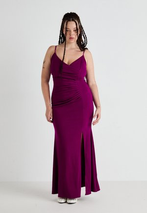 Purple, ribbed maxi dress with spaghetti straps, ruched detailing, a side slit, and smooth texture; paired with white shoes.