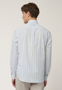 Langarmshirt met een lichtblauwe basis en verticale strepen in groen en wit. Gemaakt van stof met een zachte textuur en een klassieke kraag.