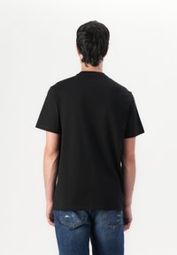 Black cotton t-shirt with short sleeves, crew neck, and a relaxed fit. The back is plain with no visible graphics or patterns.