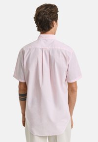 Korte mouwen, knoopsluiting shirt in lichtroze katoen, met details van een rugplooi en een gebogen zoom. Schoon ontwerp met subtiele stikselaccenten.