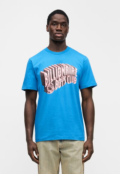 Μπλε βαμβακερό μπλουζάκι με μεγάλο ροζ γραφικό και κείμενο "Billionaire Boy Club". Κοντά μανίκια και σχέδιο με στρογγυλή λαιμόκοψη.