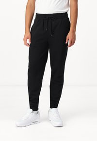 Zwarte joggingsbroek met een elastische tailleband en verstelbare trekkoord, met een tapered fit en zijzakken, gemaakt van zachte, ademende stof.