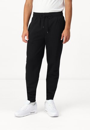 Pantalones de chándal negros con cintura elástica y cordón ajustable, que presentan un corte ajustado y bolsillos laterales, hechos de una tela suave y transpirable.