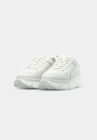 Baskets de sport blanches avec une tige en cuir lisse, bout rond, design à lacets, semelle texturée et logo subtil sur la languette.