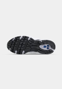 Semelle d'une chaussure de sport noire et grise avec une semelle texturée et deux accents ovales bleus près du talon sur un fond blanc.