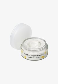 Beurre corporel dans un pot en verre transparent avec une texture crémeuse blanche. L'étiquette présente des illustrations de poissons jaunes et du texte noir. Le couvercle est blanc.