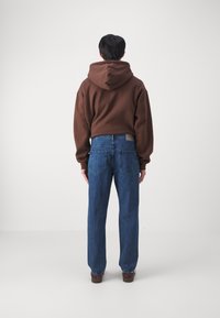 Brun hettegenser med avslappet passform, kombinert med løstsittende blå jeans med klassisk fem-lommers design.