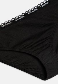 Čierne bavlnené bikini nohavičky s čipkovaným pásom s logom "Calvin Klein". Hladká textura a priliehavý strih.