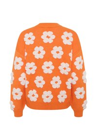 Narancssárga kötött pulóver fehér virágmintával, textúrált virágokkal, bordázott mandzsettákkal és laza szabással. A hátoldali nézet bemutatja az összes dizájnt.