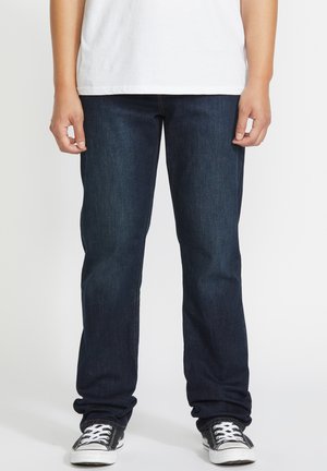 Dark blue denim jeans with a straight-leg fit, featuring a classic five-pocket design and subtle stitching details. Accompanied by black sneakers.