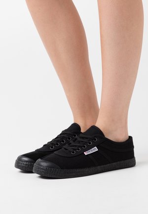 Sneaker in tela nera con punte in gomma tonde e suole texturizzate. Presenta lacci e una piccola etichetta logo sul lato. Design a taglio basso.