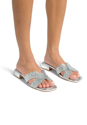 Sandali con tacco in argento dotati di cinturini incrociati adornati da gemme trasparenti; finitura metallica liscia; design open-toe; tacco a blocco.