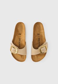 Μπεζ σανδάλια Birkenstock με φαρδιά λουρί, χρυσή αγκράφα και περιμετρικό φελλό πάτο. Λείο υλικό στο ανώτερο μέρος, ανοιχτή φτέρνα. Μέγεθος 38.