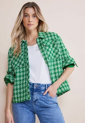 Groene en witte gestreepte jas met een kraagontwerp, voorzien van knoopsluitingen en opgerolde mouwen, gedragen over een witte top en blauwe jeans.