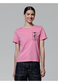 Rosa Baumwoll-T-Shirt mit kurzen Ärmeln, ausgestattet mit einem schwarzen Grafikdesign einer Figur und dem Text "THE FOOL" auf der linken Brust.