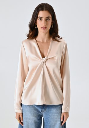 Blassrosa Satinbluse mit V-Ausschnitt und einer vorderen Knotendetail. Lange Ärmel mit Knöpfen an den Manschetten. Glatte Textur, semi-fitted Form.