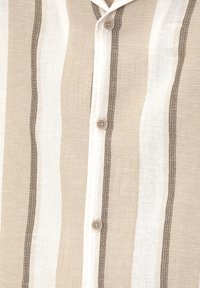 Camicia leggera con bottoni caratterizzata da strisce verticali beige e bianche alternate, con un tessuto testurizzato e cuciture di accento marroni.